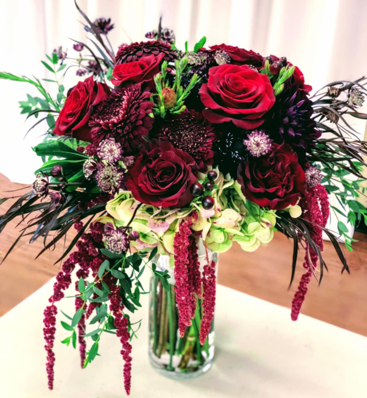 a bridal bouquet made of fresh flowers with dramatic, textured flowers in red and burgundy tones.